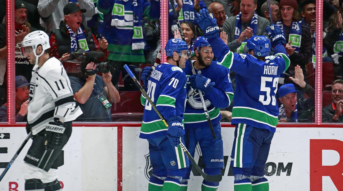 The Vancouver Canucks celebrate a goal as Kings captain Anze Kopitar skates past during the Kings' 8-2 loss Wednesday.