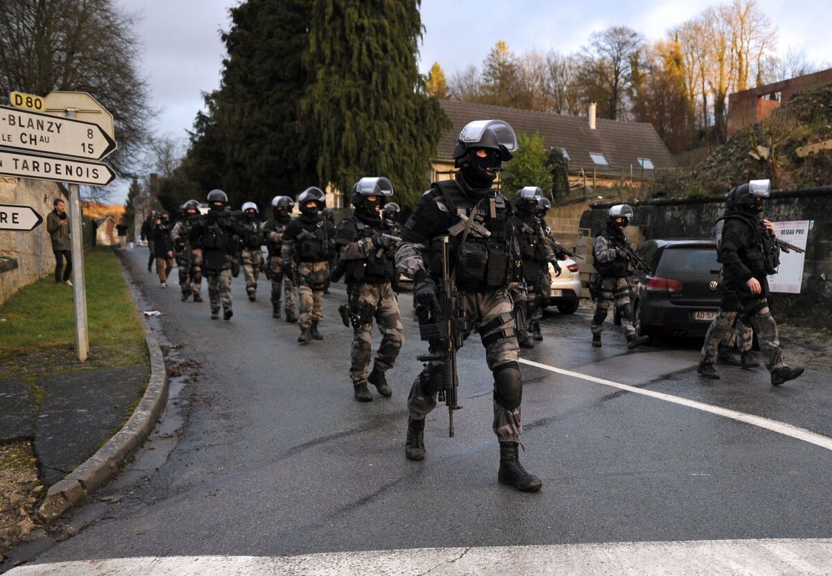 Members of the police special forces walk through Corcy, in northern France, during a manhunt Jan. 8 for the gunmen behind a deadly attack at the offices of a Paris satirical weekly.
