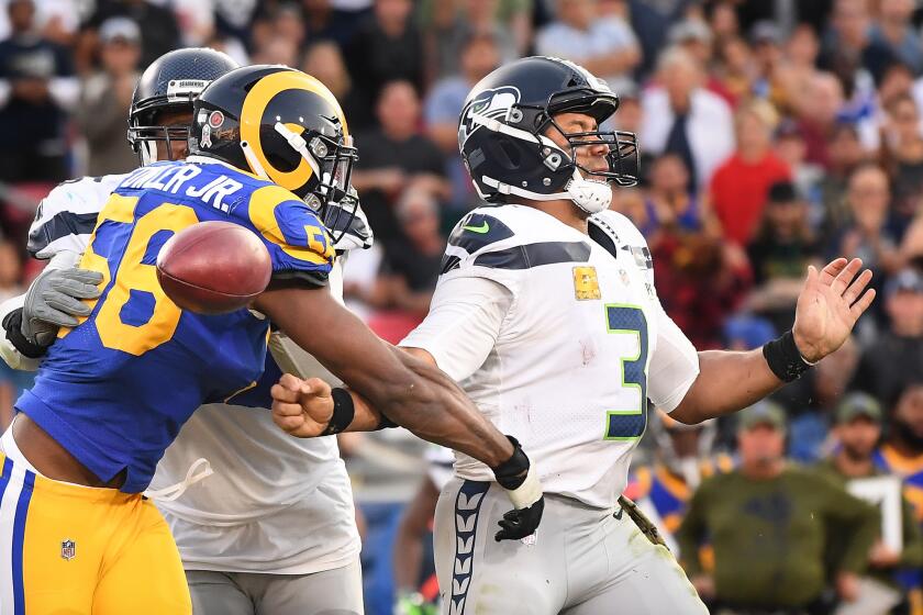 Rams linebacker Dante Fowler forces a fumble on Seattle Seahawks quarterback Russell Wilson in the fourth quarter at the Coliseum on Sunday.