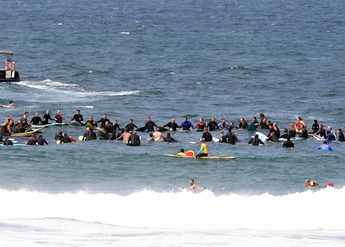 Surfers hold hands and form a circle in the ocean to pay tribute to the late Brian Wilson.