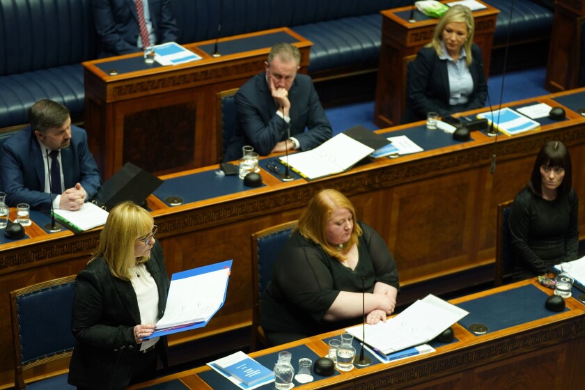 Education Minister Michelle McIlveen, from the Democratic Unionist Party, left, delivers her speech in the Northern Ireland Assembly chamber at Stormont, in Belfast, Northern Ireland, Friday, March 11, 2022. The Northern Ireland government issued a formal apology on Friday to people who were abused in orphanages and children’s homes, telling them “the state let you down.” Ministers from all five political parties in the Northern Ireland Assembly read out apologies to survivors gathered at the Stormont government buildings near Belfast. (Brian Lawless/PA Wire(/PA via AP)