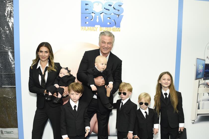 A family of six poses in suit on a blue carpet for a movie premiere