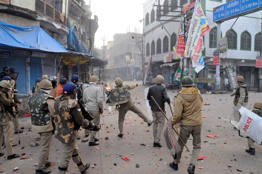 A police officer throws stones toward protesters in Kanpur during demonstrations against India’s new citizenship law on Dec. 21.