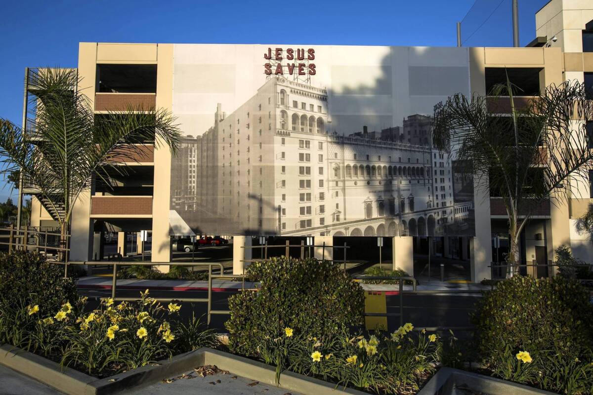 A smaller replica of the iconic "Jesus saves" sign is incorporated into a giant photographic mural on the side of a Biola University parking structure.