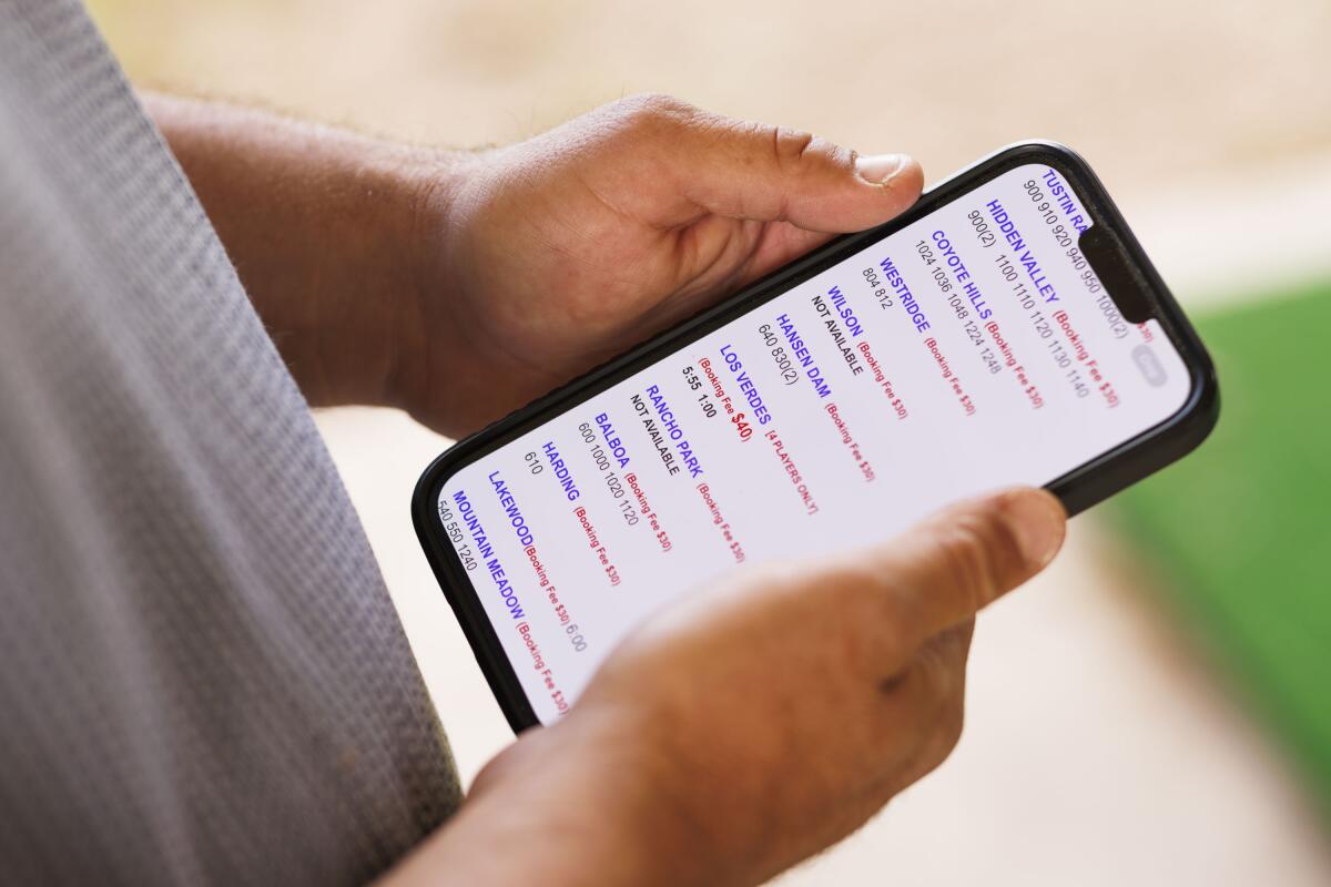 Hands hold a cellphone displaying a screenshot of a golf course broker's booking page.