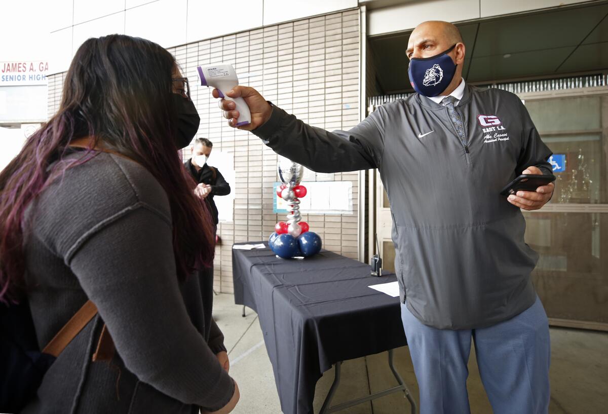 A freshman has her temperature checked before her first day back on campus at James A. Garfield High School