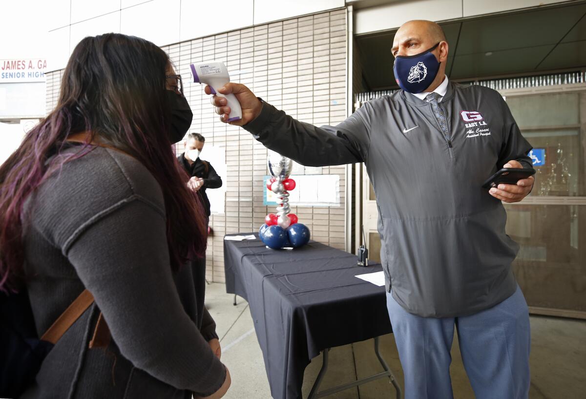 A freshman has her temperature checked before her first day back on campus at James A. Garfield High School 