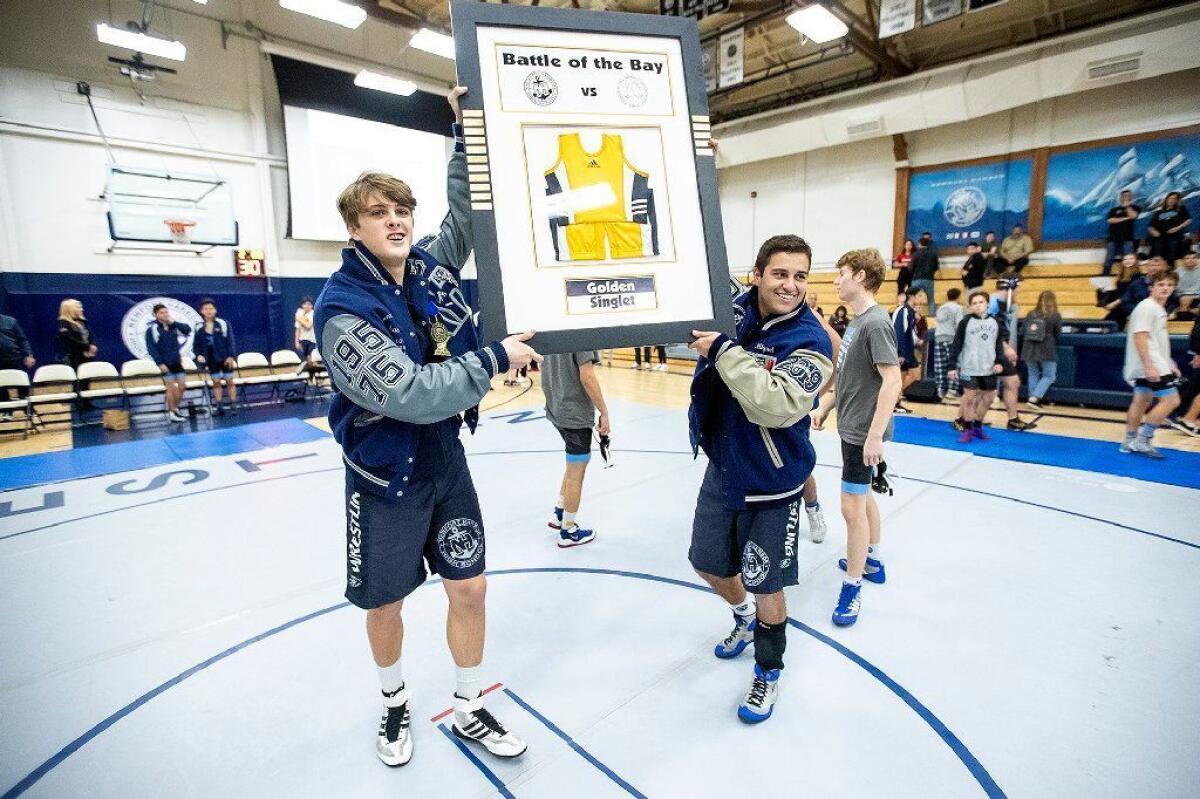 Newport Harbor's Austin Osumi, left, and Miguel Licona hold up the Golden Singlet after beating Corona del Mar 56-18 in a Wave League match on Jan. 9. Osumi set school records for pins in a career and pins in a single season.