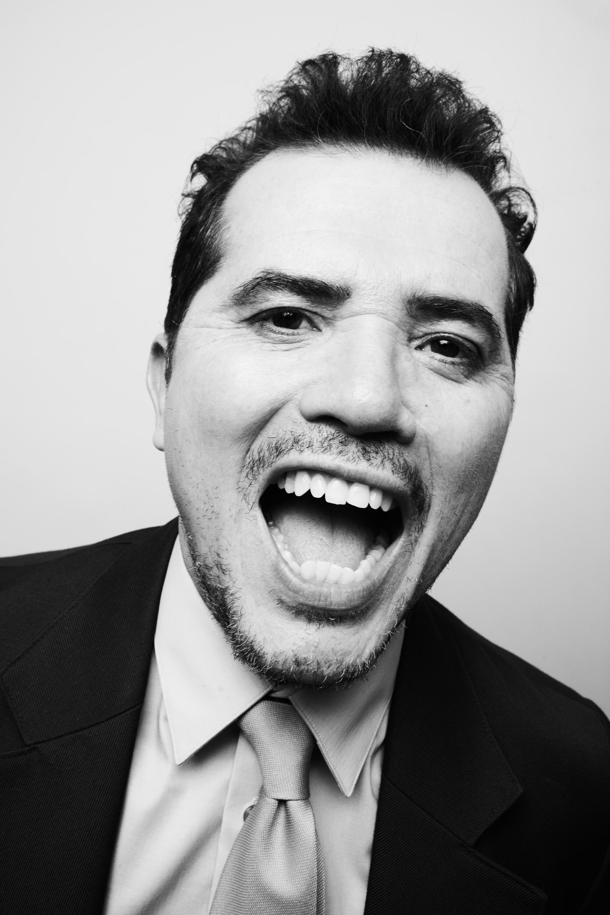 A black-and white portrait of John Leguizamo with his mouth wide open.
