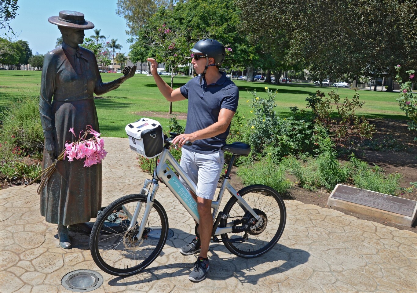 In Balboa Park, Ike Fazzio of San Diego Fly Rides, on one of his company's electric-assist bikes, greets the statue of Kate Sessions, the botanist often called "Mother Balboa" for her work in helping to create the park.