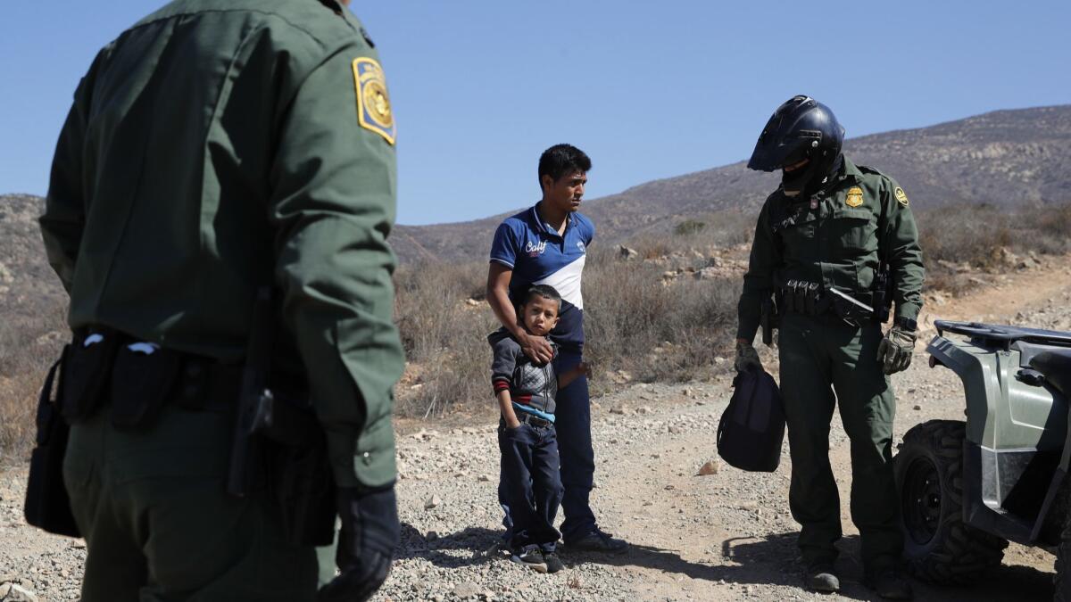 A Guatemalan father and son, who crossed the U.S.-Mexico border illegally, are apprehended by U.S. Border Patrol agents on June 28 in San Diego.