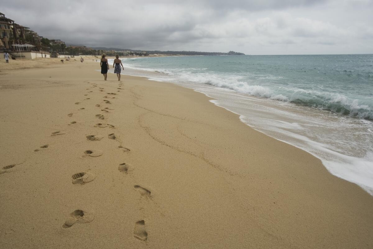 Tourists walk on the beach in Cabo San Lucas, in Mexico