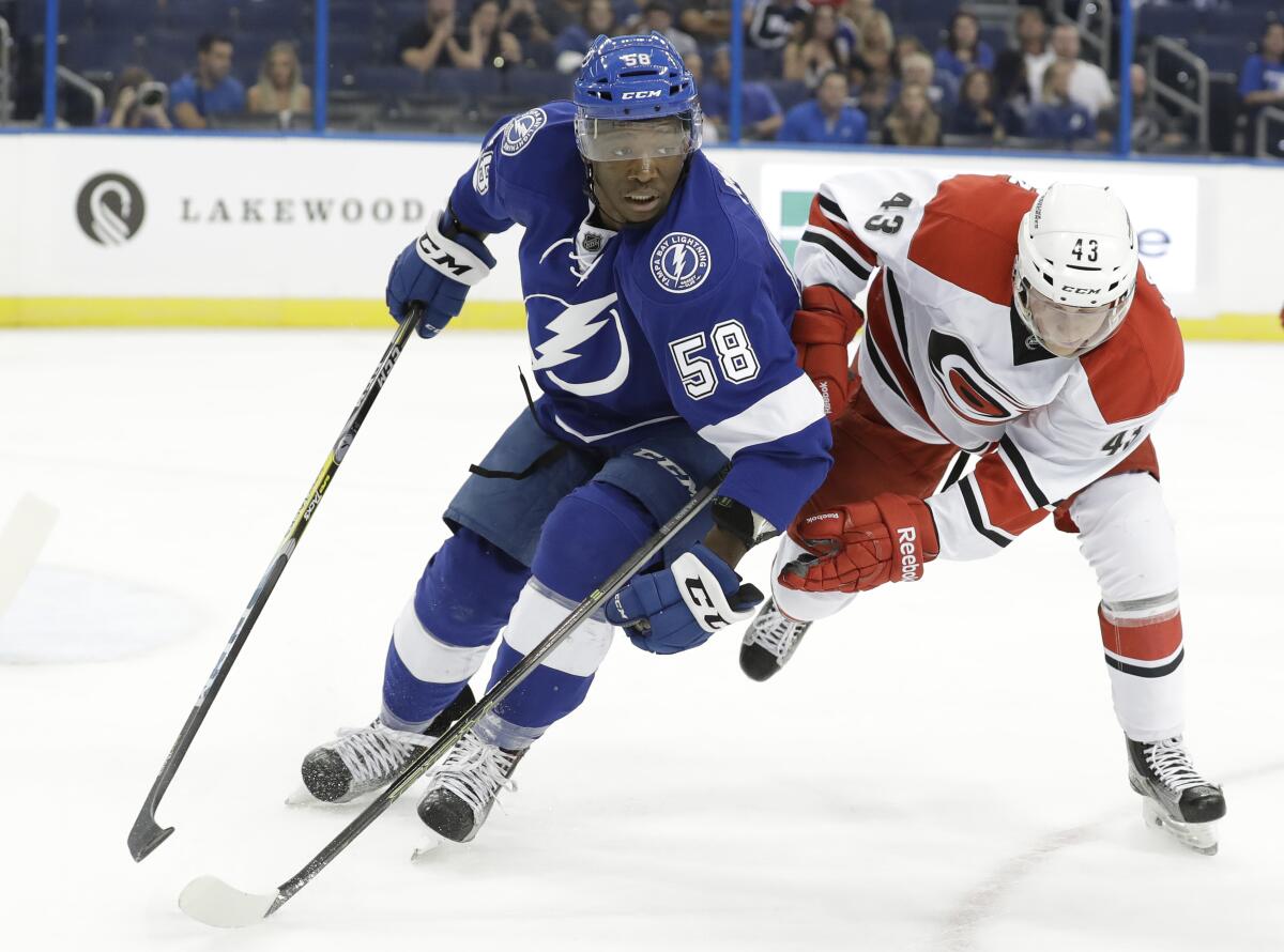 Tampa Bay Lightning forward Bokondji Imama, left, and Carolina Hurricanes forward Erik Karlsson chase after the puck.