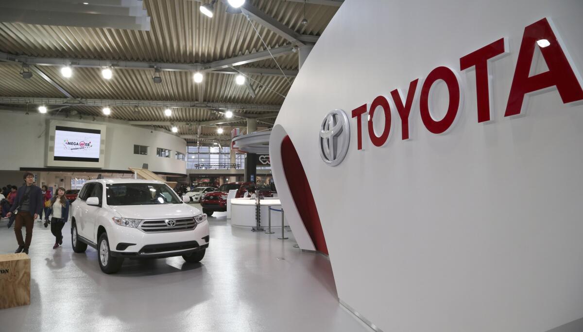 Visitors inspect Toyotas at a gallery in Tokyo. The Japanese automaker stayed at the top in global vehicle sales in 2014 but is pessimistic about this year because of expected weaker sales in Japan.