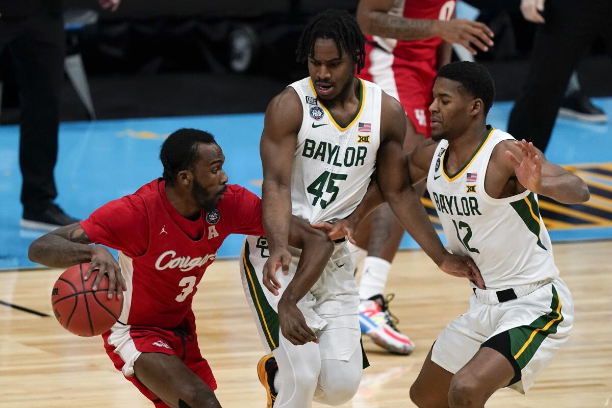 Houston guard DeJon Jarreau (3) drives around Baylor guard Davion Mitchell (45) and guard Jared Butler (12) during the first half of a men's Final Four NCAA college basketball tournament semifinal game, Saturday, April 3, 2021, at Lucas Oil Stadium in Indianapolis. (AP Photo/Michael Conroy)