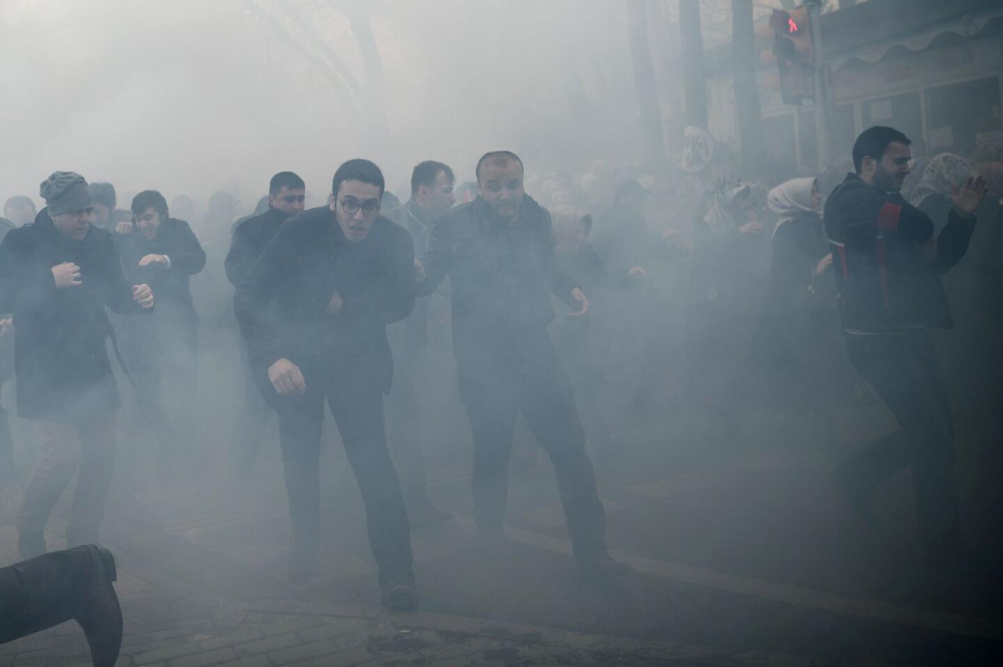 Demonstrators run as Turkish riot police use tear gas to disperse supporters of the Zaman newspaper in front of its headquarters in Istanbul on March 5, 2016, after a court ordered the seizure of the paper's parent company by government trustees.