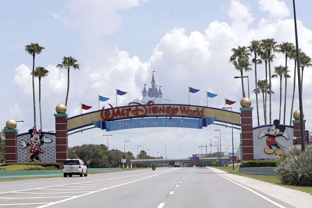 FILE - Cars drive under a sign greeting visitors near the entrance to Walt Disney World, July 2, 2020, in Lake Buena Vista, Fla. The first meeting of the new board of Walt Disney World’s government — overhauled by sweeping legislation signed by Republican Gov. Ron DeSantis as an apparent punishment for Disney publicly challenging Florida’s so-called “Don’t Say Gay” bill — dealt with the rote affairs any other municipal government handles. Board members on Wednesday, March 8, 2023, faced calls for better firefighter equipment, lessons on public records requests and bond ratings. (AP Photo/John Raoux, File)