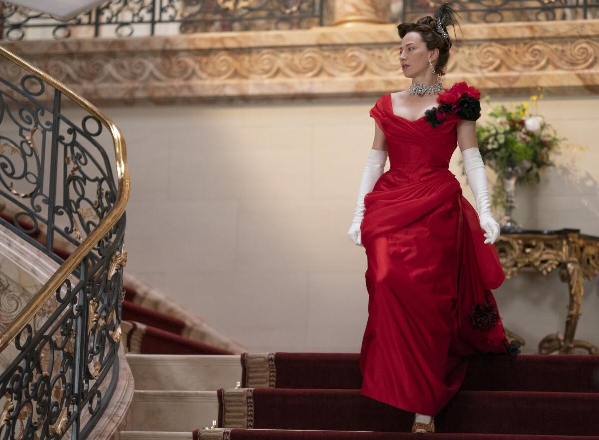  woman in a red dress walks down a grand staircase