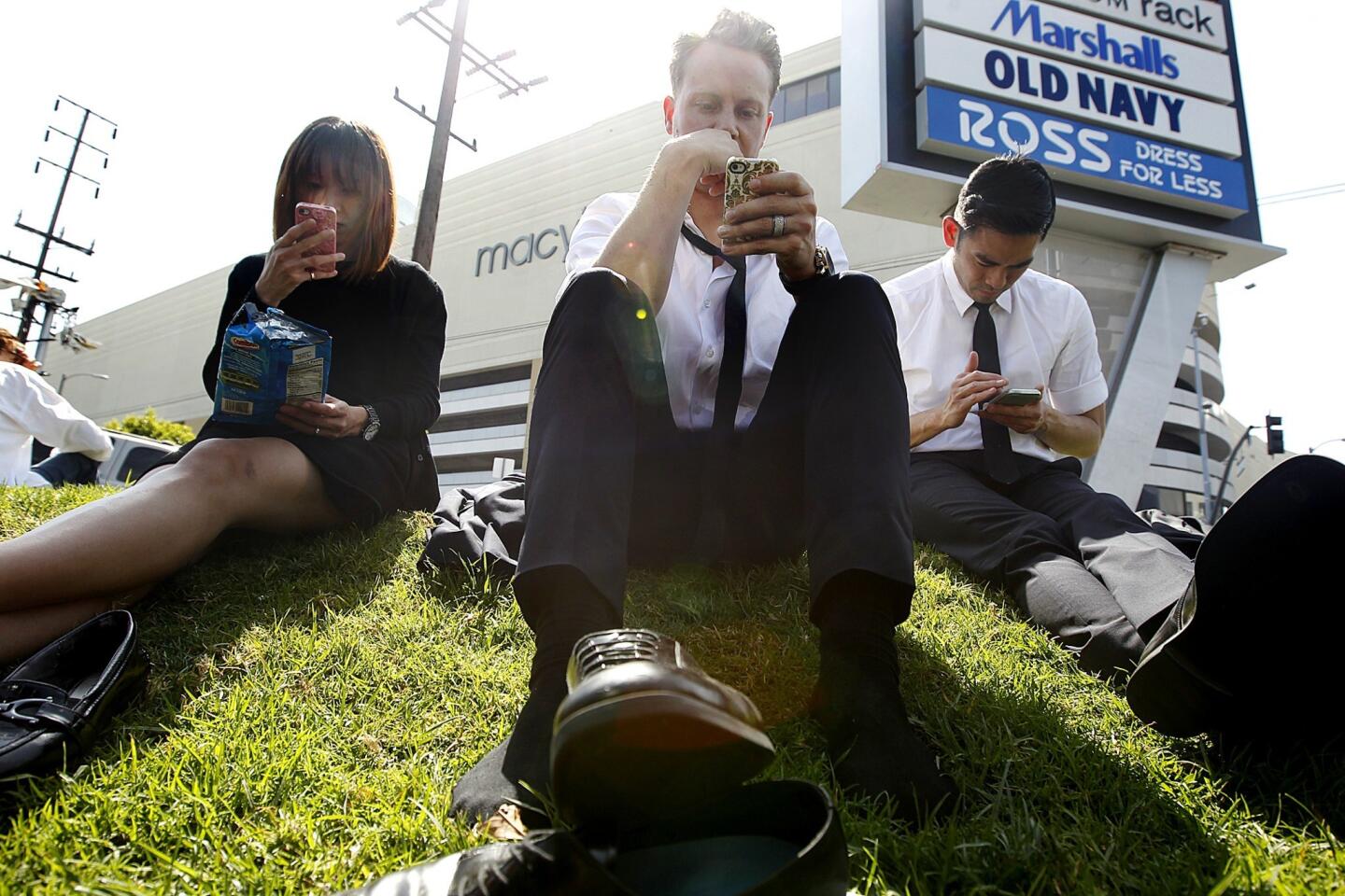 Prada employees wait patiently across the street from the Beverly Center in Los Angeles after the shopping mall was evacuated due to a suspicious package in the attached parking garage on Sunday.