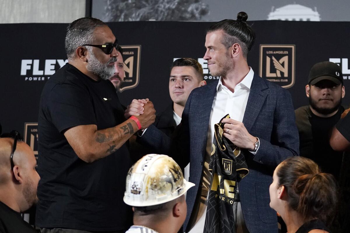 Gareth Bale, right, shakes hands with a fan during a news conference Monday.