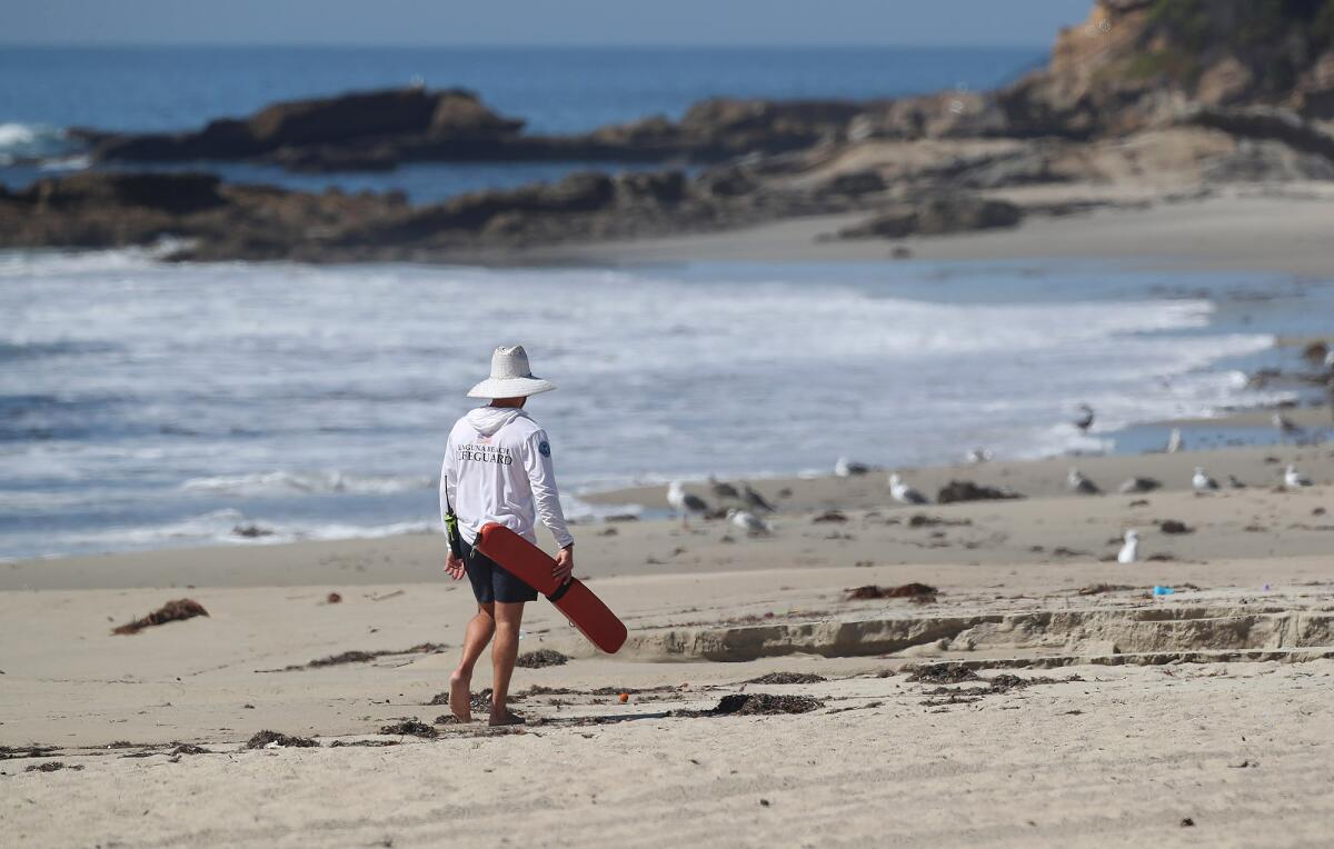 A Laguna Beach lifeguard walks the empty sands of Main Beach in October. 