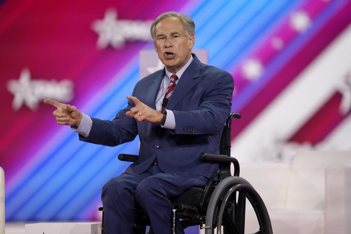 Texas Gov. Greg Abbott speaks on a stage while pointing.