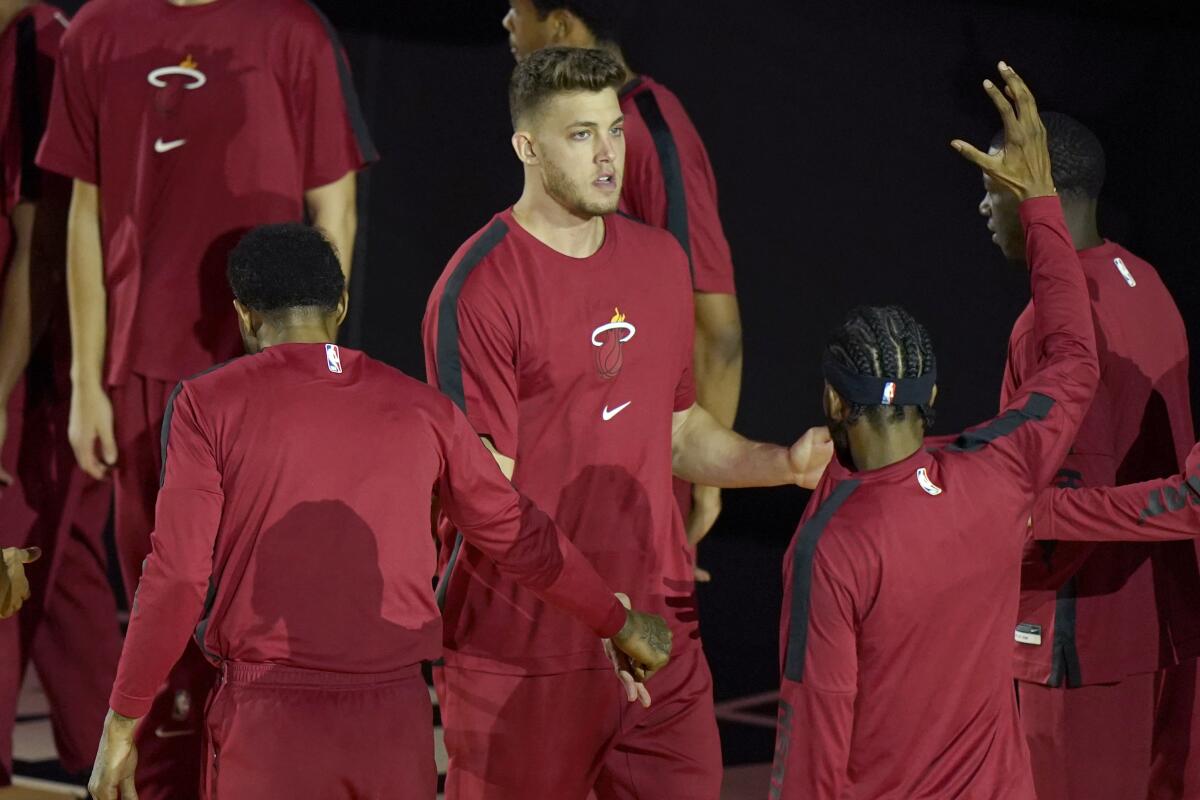 Miami Heat forward Meyers Leonard, center, greets his teammates before a game against the Milwaukee Bucks.