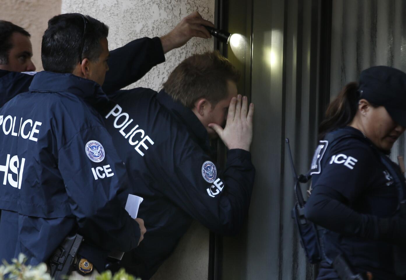 ICE agents from the Department of Homeland Security look into the window of an apartment in Rowland Heights while executing search warrants during the ongoing investigation of "birth tourism" centers.