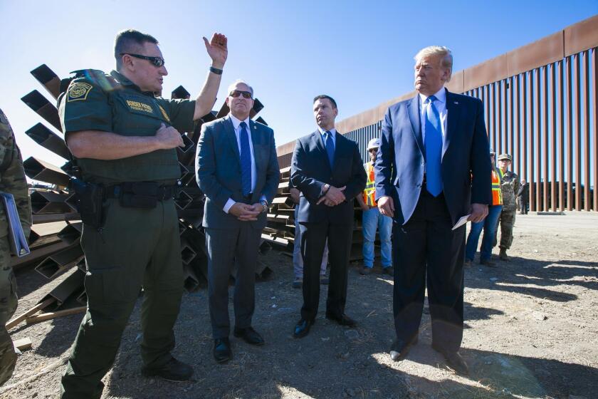 John Gibbins  U-T Douglas Harrison (left), with the Border Patrol in the San Diego Sector, explains some design details of the new border fencing to President Donald Trump near the Otay Mesa Port of Entry on Wednesday. “It’s an amazing project,” Trump said.