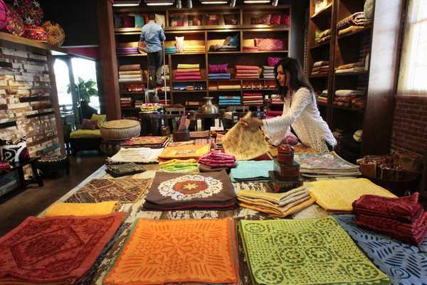 Deepali Pareek, owner of De-Cor in Pasadena, organizes the collection of handmade pillow covers, which range from $24 to $69. In the background, sales director Ricardo Chavez Jr. tidies shelves of bedding and raw fabrics.