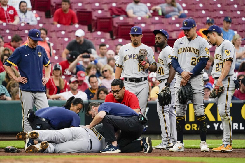 Training staff attend to Milwaukee Brewers' Travis Shaw during the second inning of the team's baseball game against the Cincinnati Reds in Cincinnati on Wednesday, June 9, 2021. (AP Photo/Jeff Dean)