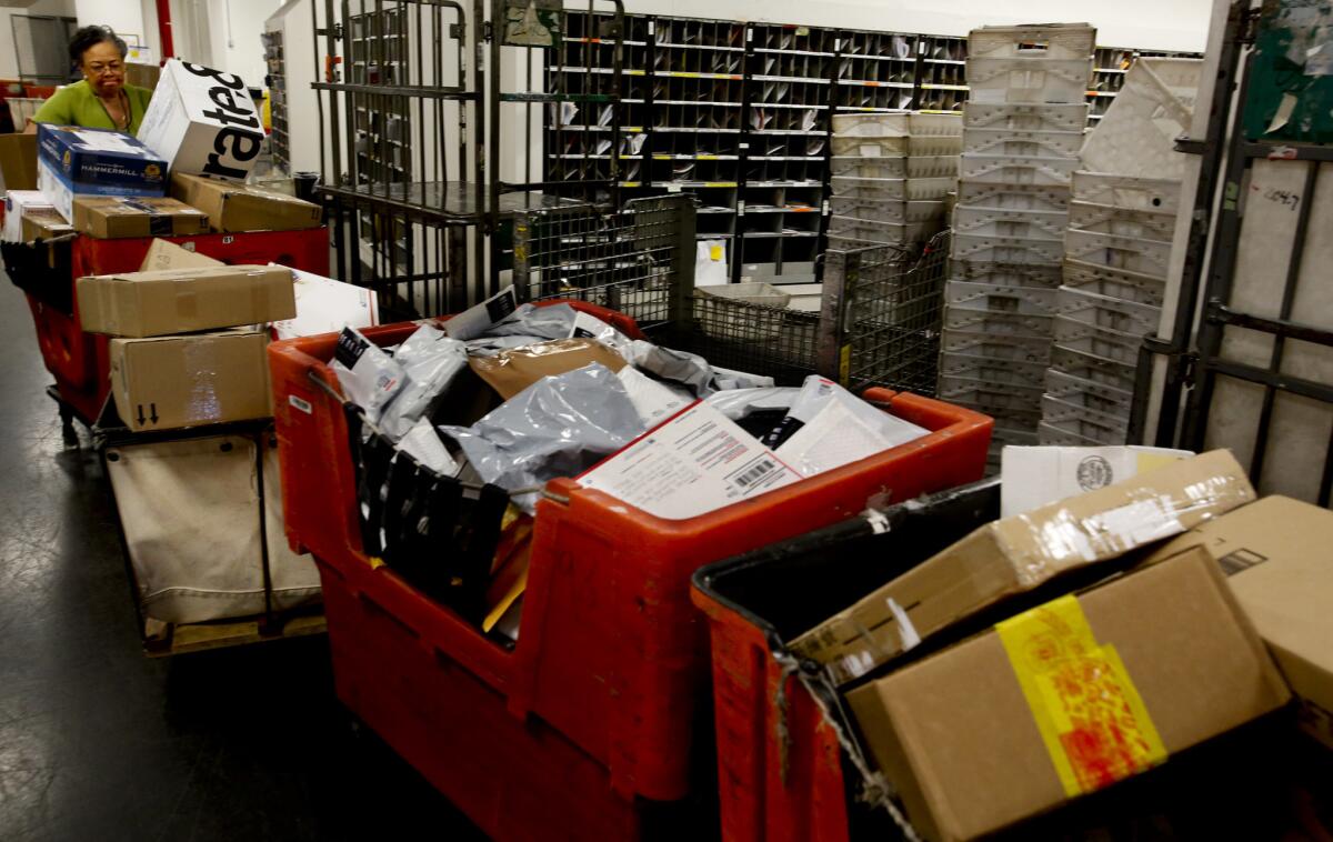 A supervisor moves packages behind the scenes at the U.S. Postal Service's Airport Station.