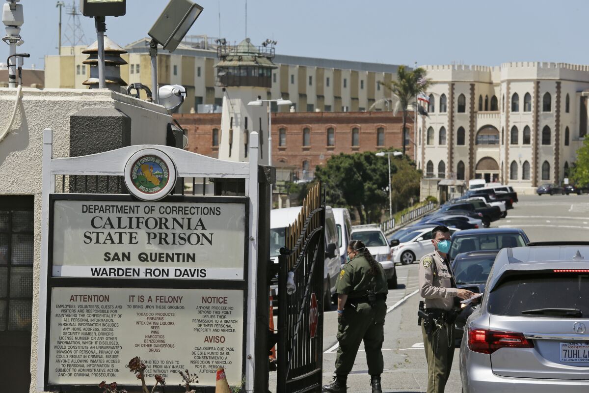 A correctional officer checks a car entering the main gate of San Quentin State Prison in San Quentin, Calif. 