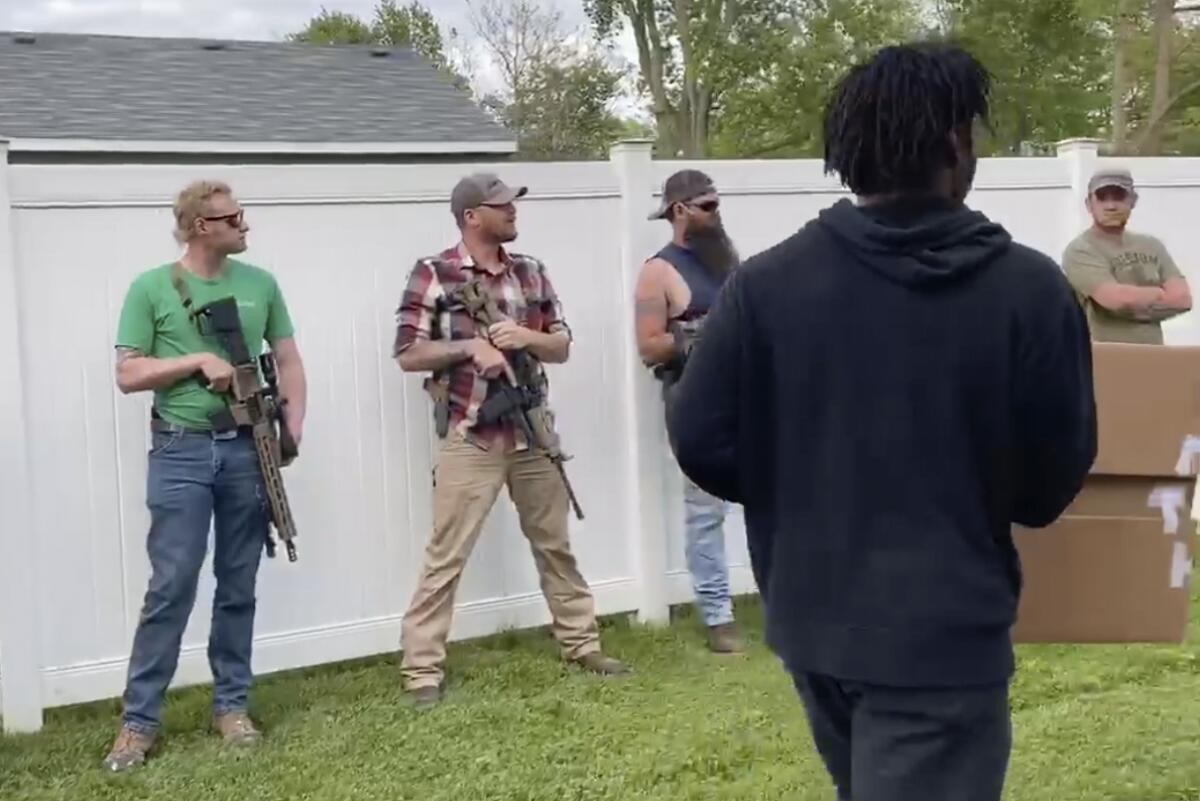 Demonstrators against police brutality and racism encounter armed bystanders as they march in Crown Point, Ind.