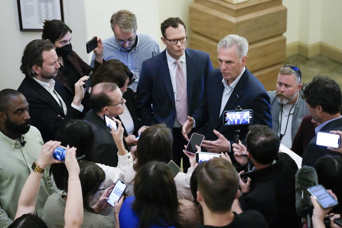 House Speaker Kevin McCarthy standing and talking, surrounded by members of the news media
