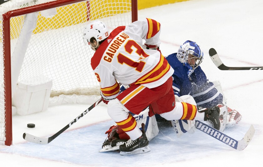Calgary Flames' Johnny Gaudreau (13) scores the game winning goal on Toronto Maple Leafs goaltender David Rittich (33) in overtime of an NHL hockey game Tuesday, April 13, 2021 in Toronto. (Frank Gunn/Canadian Press via AP)