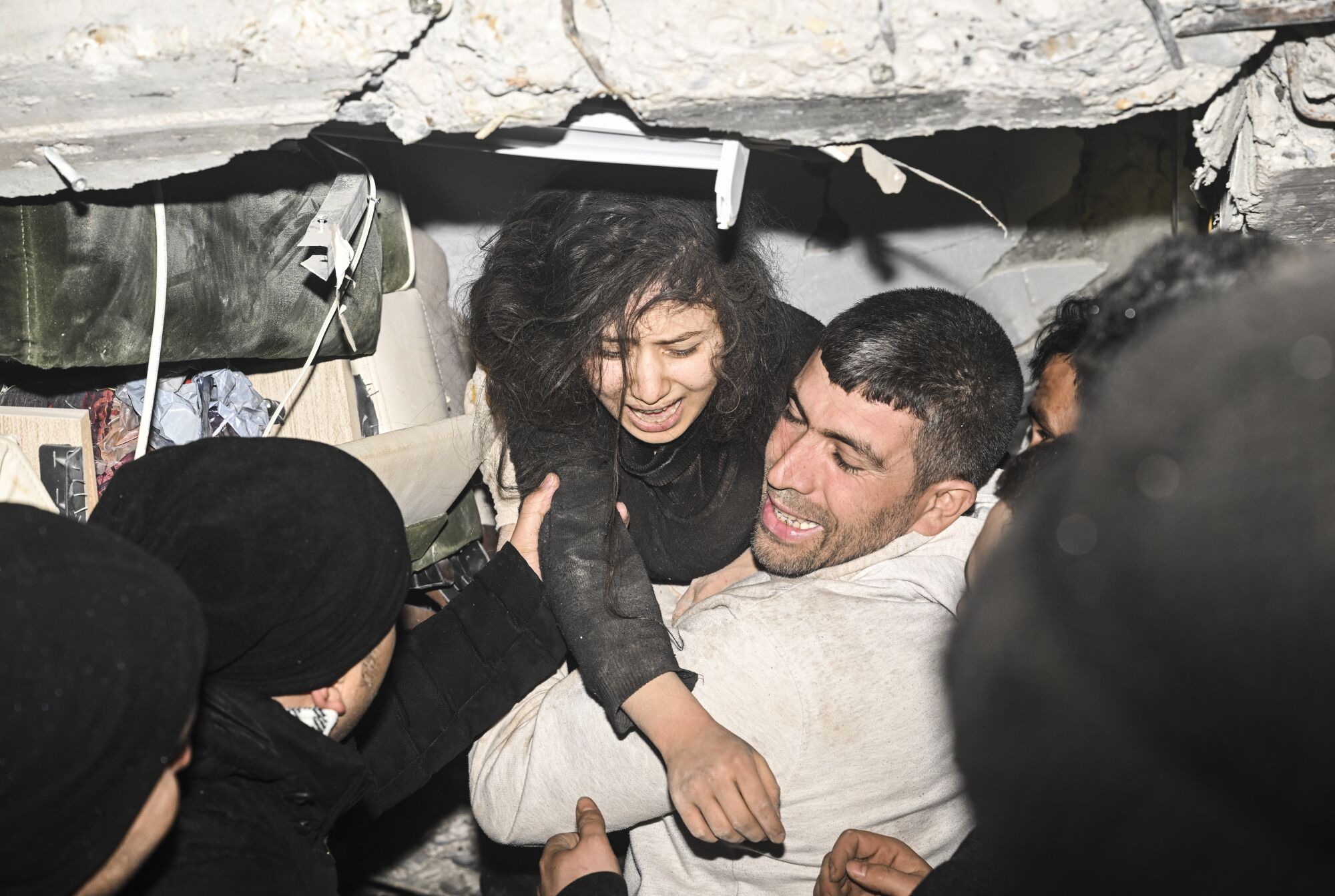 A crying teen girl is pulled out from under rubble of a collapsed building
