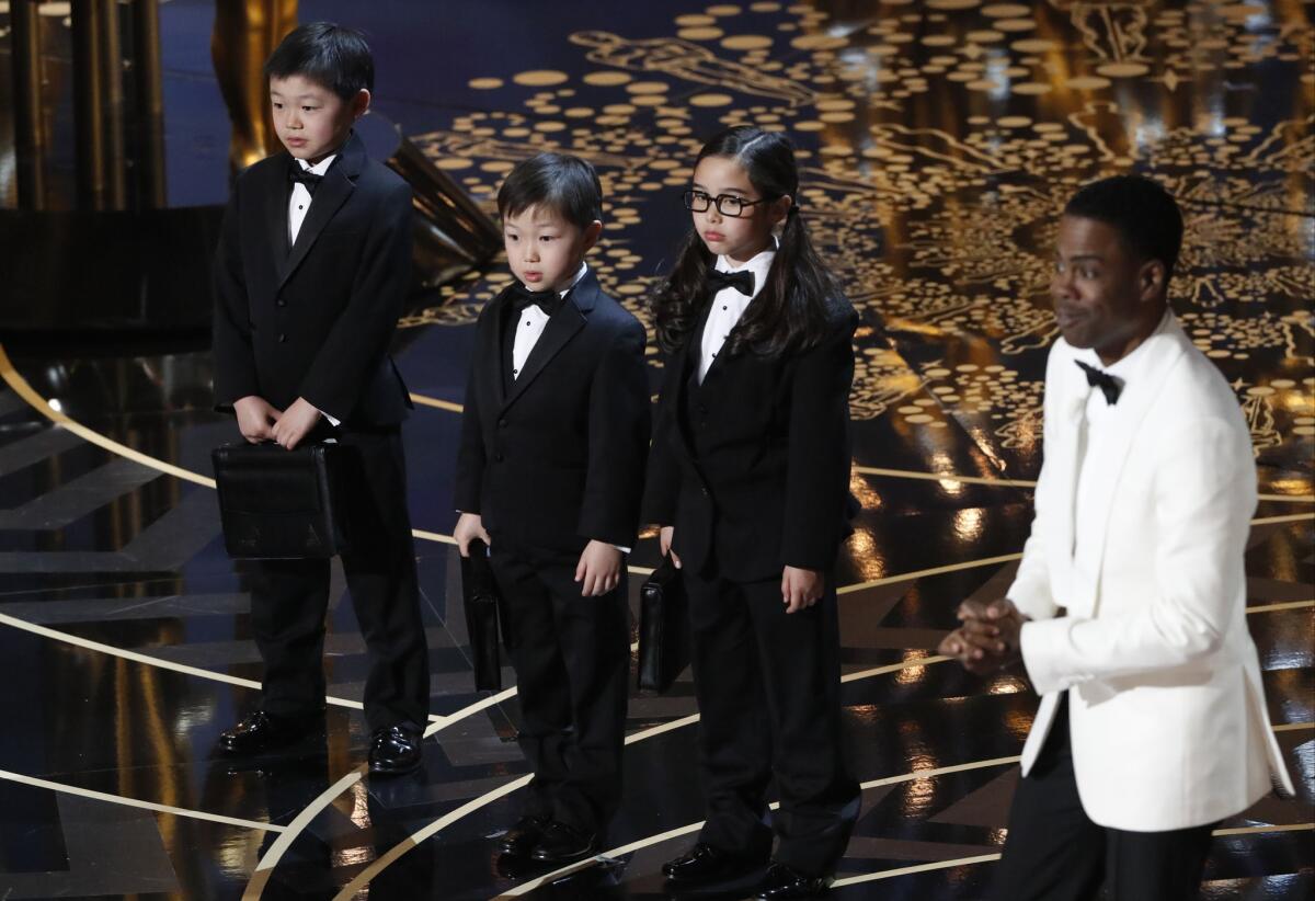Oscars host Chris Rock, right, introduces three Asian children as Price Waterhouse representatives during a controversial spoof at the 88th Academy Awards.