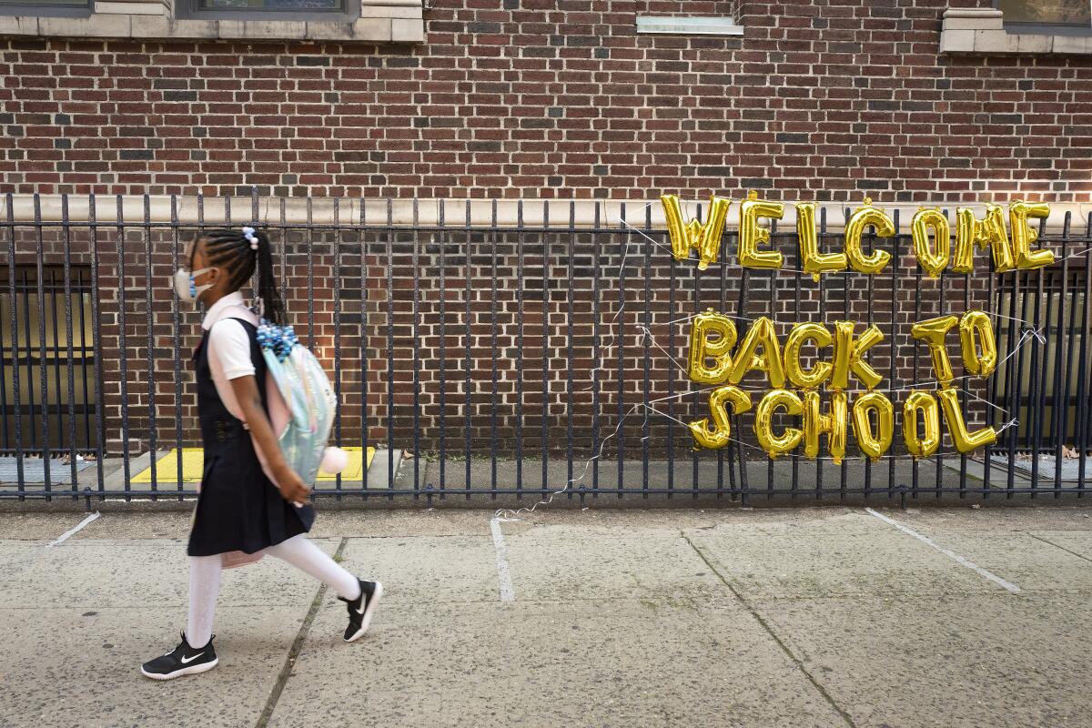 A student passes a "welcome back to school" sign on her way to class in New York. 