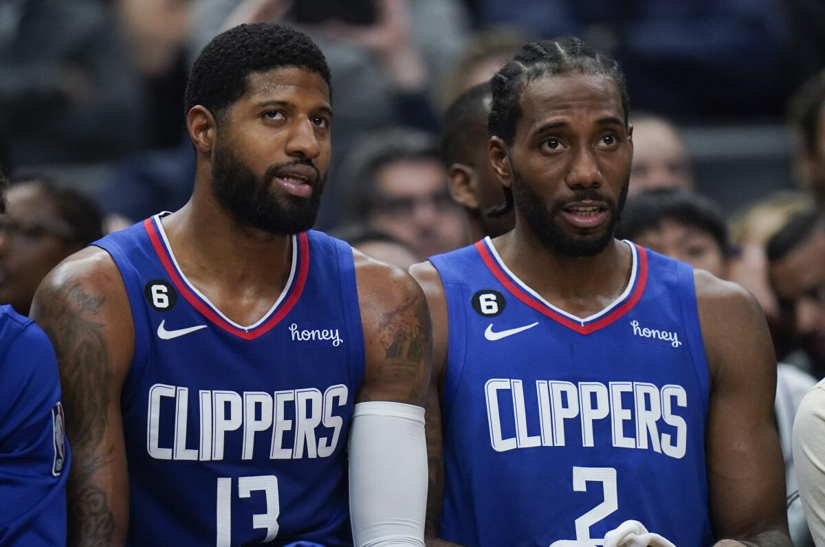 Paul George, left, and Kawhi Leonard sit on the bench.