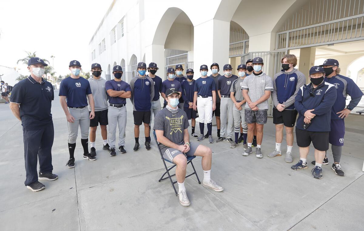 Newport Harbor baseball player Kaden Stowell, sits surrounded by his team after signing to attend Colorado Springs.