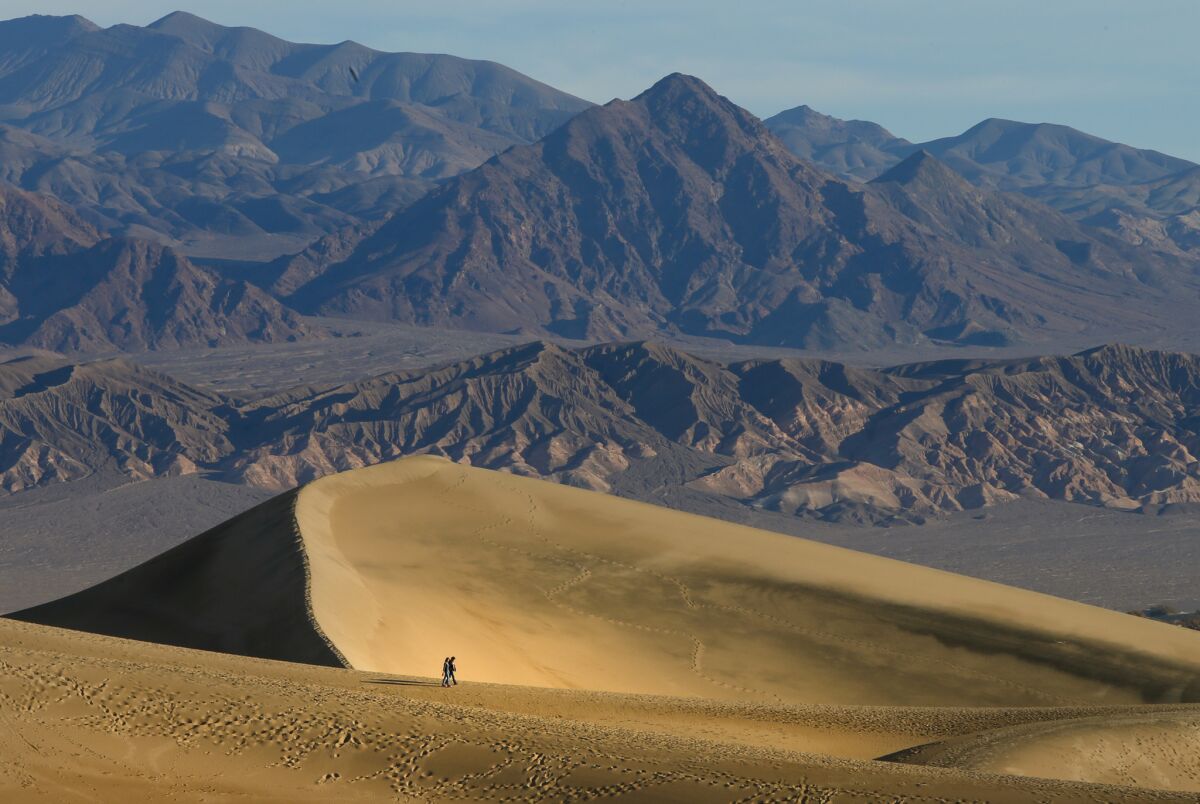 Two people walking near sand dunes at Death Valley