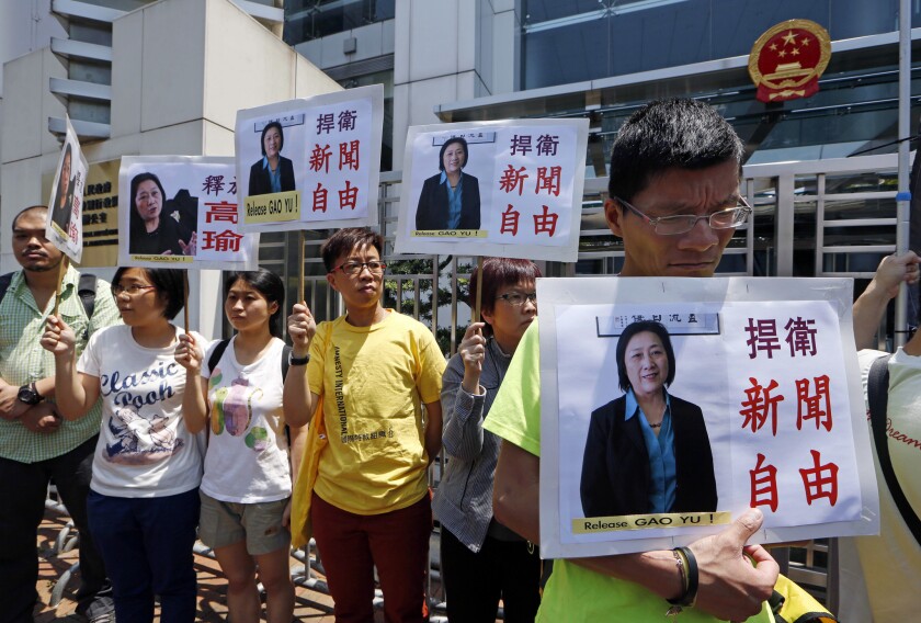 In this April 17, 2015, file photo, protesters hold pictures of jailed veteran Chinese journalist Gao Yu during a rally outside Chinese central government's liaison office in Hong Kong. The placards read, "Defend press freedom."