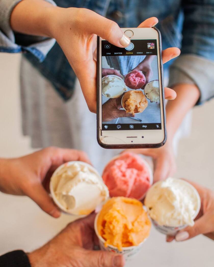 Orang-orang memegang empat cangkir es krim untuk berfoto
