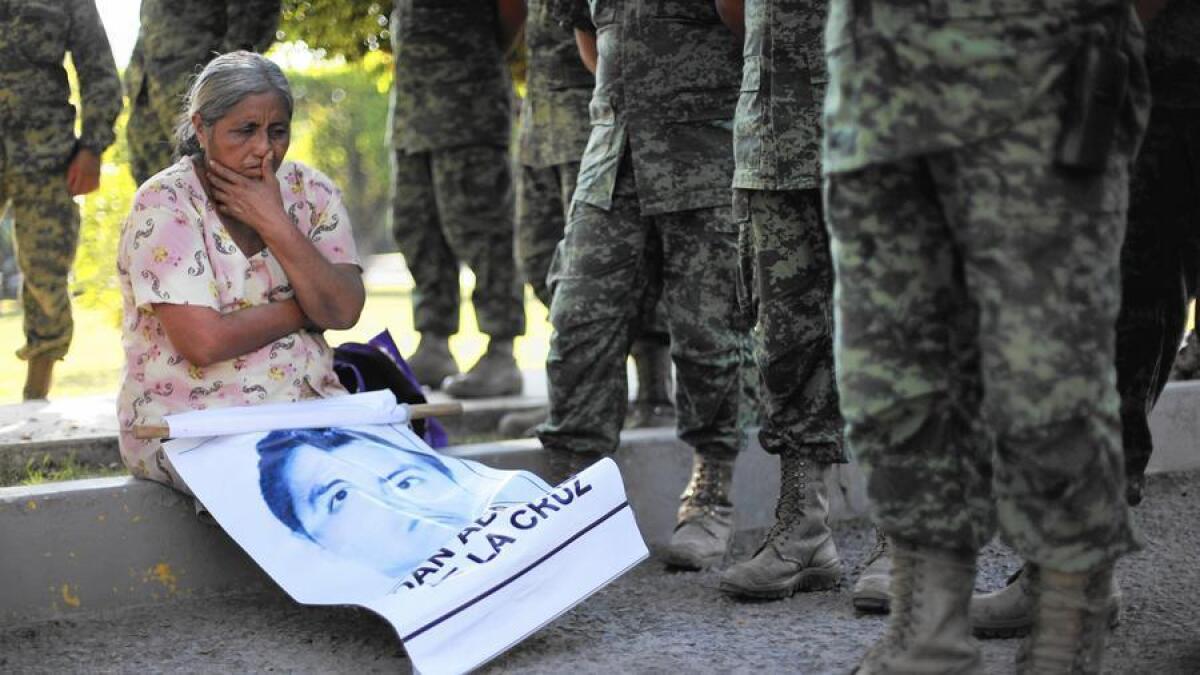 En diciembre, una mujer se sienta con una foto de su hijo durante una protesta protagonizada por las familias de los 43 estudiantes que desaparecieron el año pasado en Iguala, México