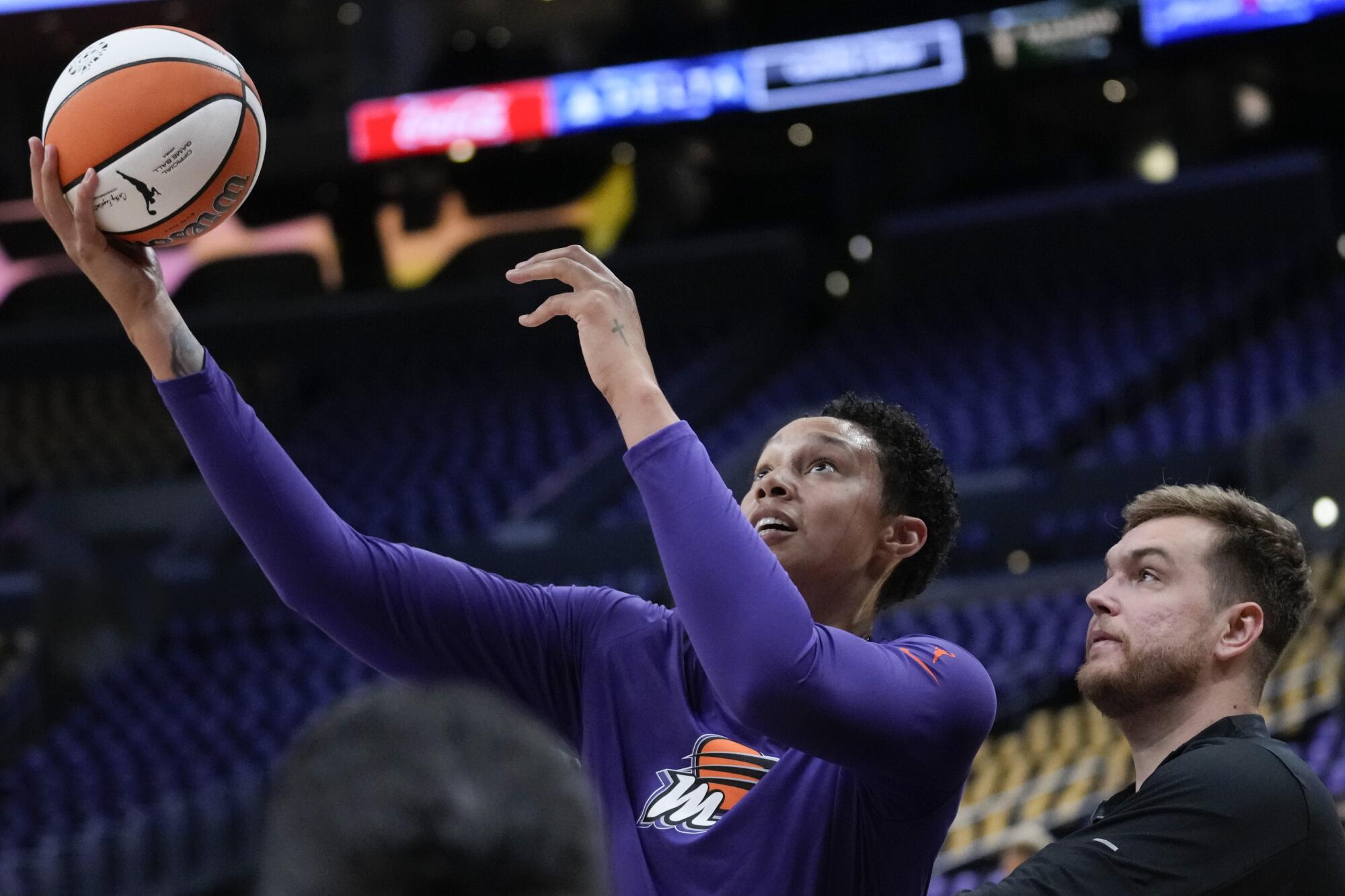Phoenix Mercury center Brittney Griner shoots a ball under pressure from a staff member as she warms up.