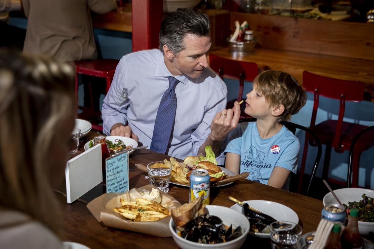 Gavin Newsom feeds his son Hunter, 6, a French fry during lunch with his family and Oakland Mayor Libby Schaaf.