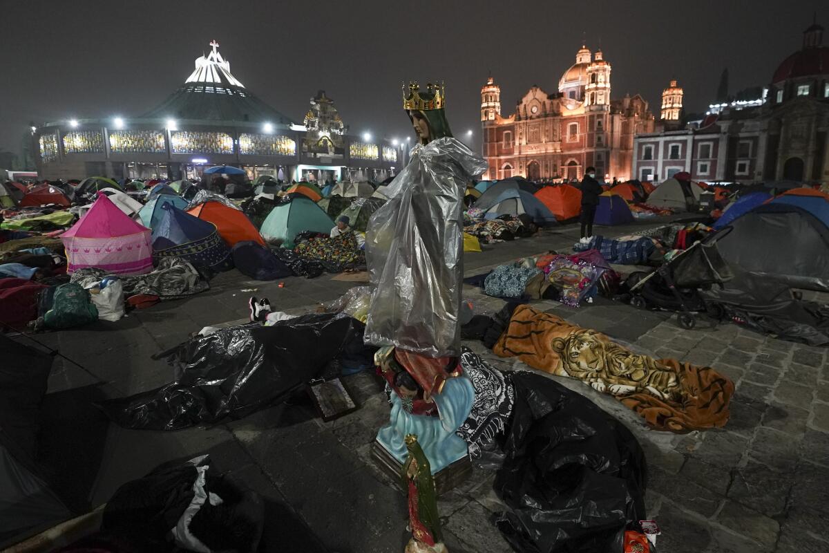 People in tents, sleeping bags and blankets in a large plaza.