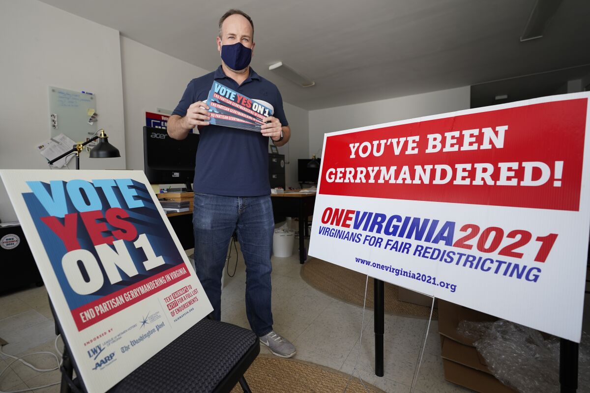 FILE - In this Oct. 6, 2020, file photo, redistricting reform advocate Brian Cannon poses with some of his yard signs and bumper stickers in his office in Richmond, Va. Negotiations broke down Friday, Oct. 8, 2021, between members of Virginia's bipartisan redistricting commission after Democrats and Republicans failed to agree on which proposed maps they should use as a starting point. (AP Photo/Steve Helber, File)