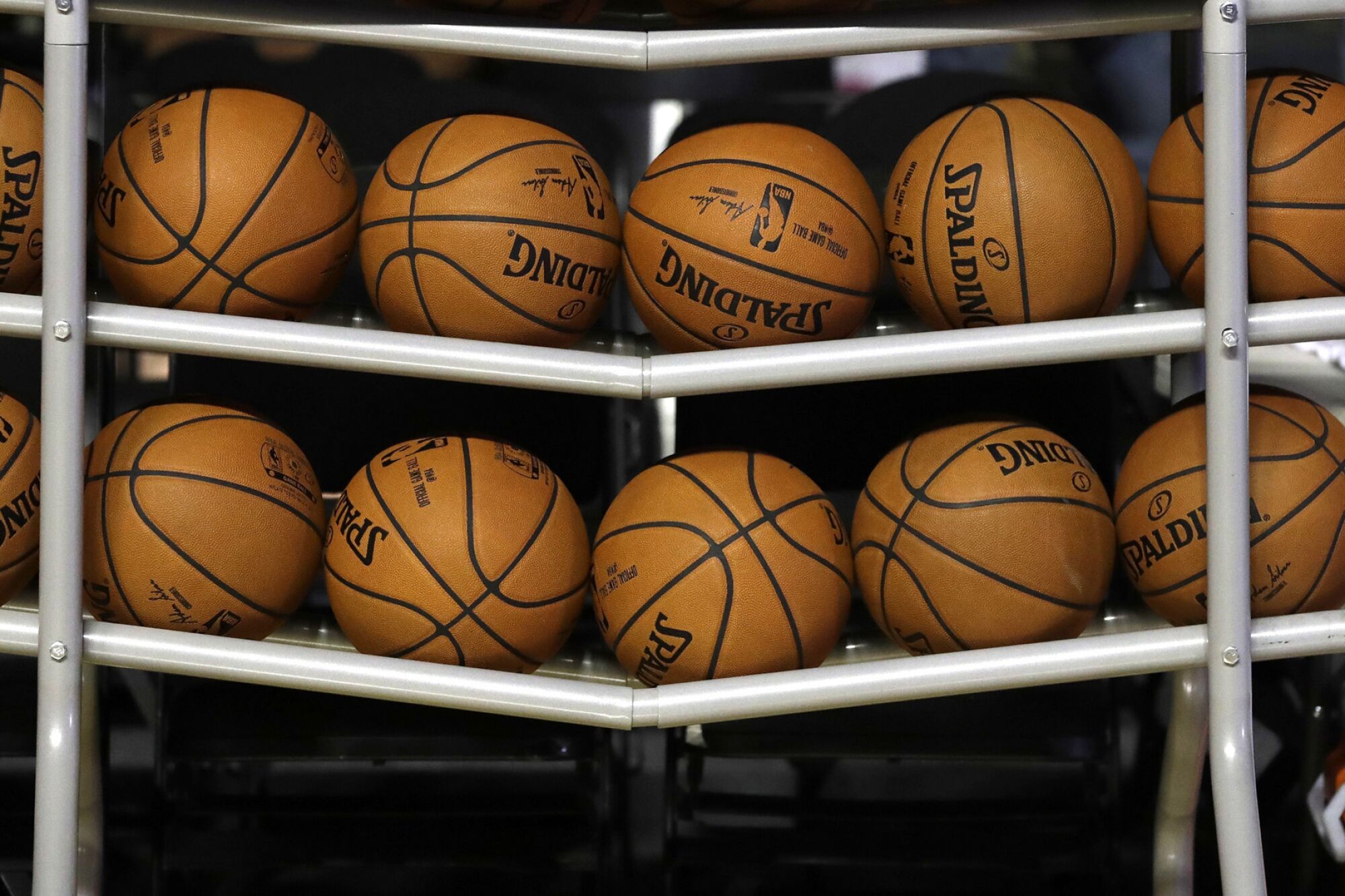 Basketballs sit in a rack on the court